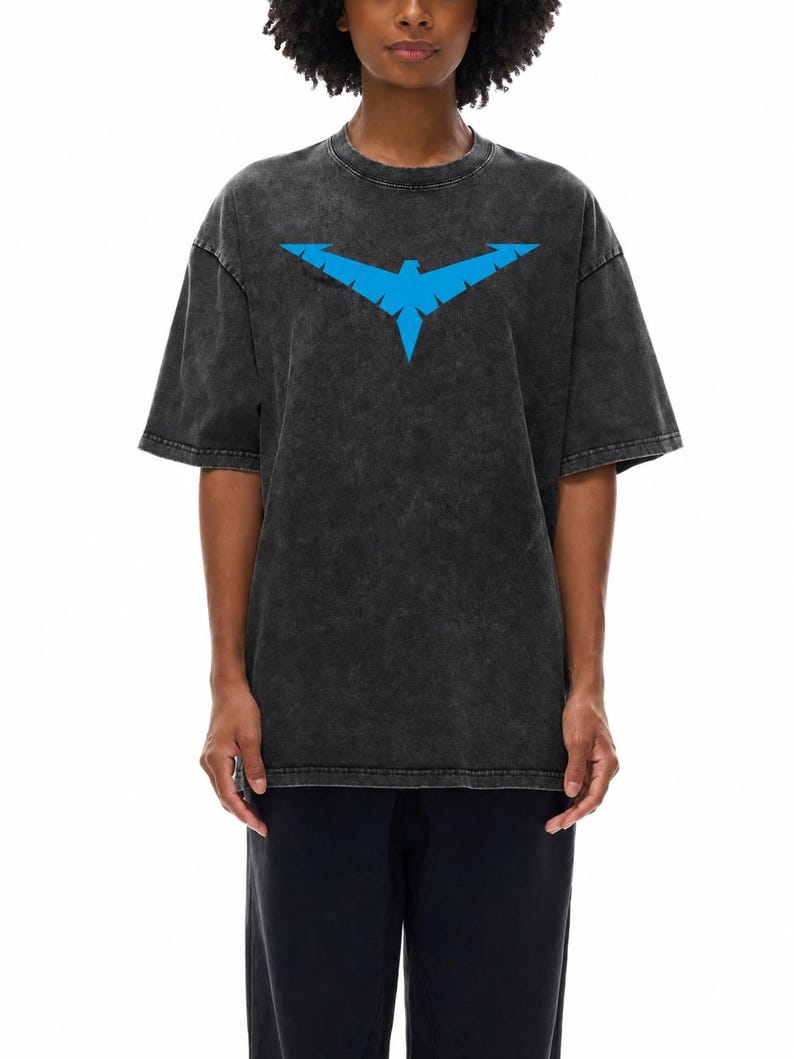 May include: Dark gray t-shirt featuring a blue stylized bird emblem. The shirt has a vintage, washed appearance and a crew neck. The short-sleeved top is paired with black pants. The graphic is centered on the chest.