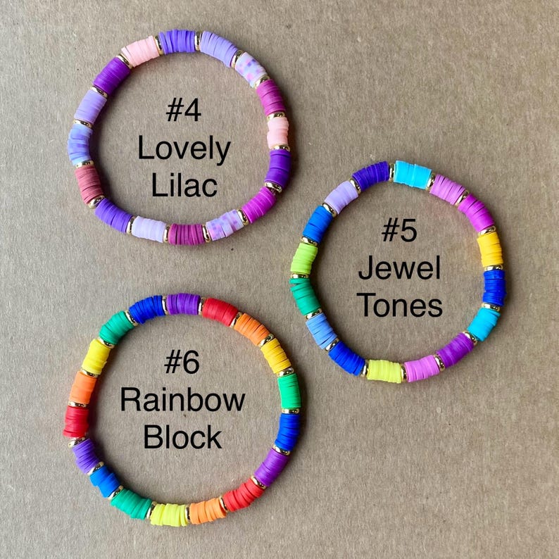 May include: Three colorful beaded bracelets. One is labeled "#4 Lovely Lilac" with purple, pink, and gold accents. Another is "#5 Jewel Tones" with blue, green, and yellow beads. The third is "#6 Rainbow Block" with a rainbow of colors.