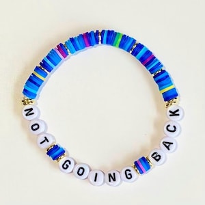 May include: A colorful beaded bracelet with the words "NOT GOING BACK" spelled out in black letters on white beads.