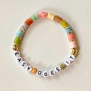 May include: A colorful beaded bracelet with the words "Easy Does It" spelled out in white beads.