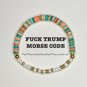 May include: A beaded bracelet with the text "FUCK TRUMP MORSE CODE" in black. The bracelet features colorful orange, teal, and gold beads, with white and gold beads at the bottom. The Morse code is written below the text.
