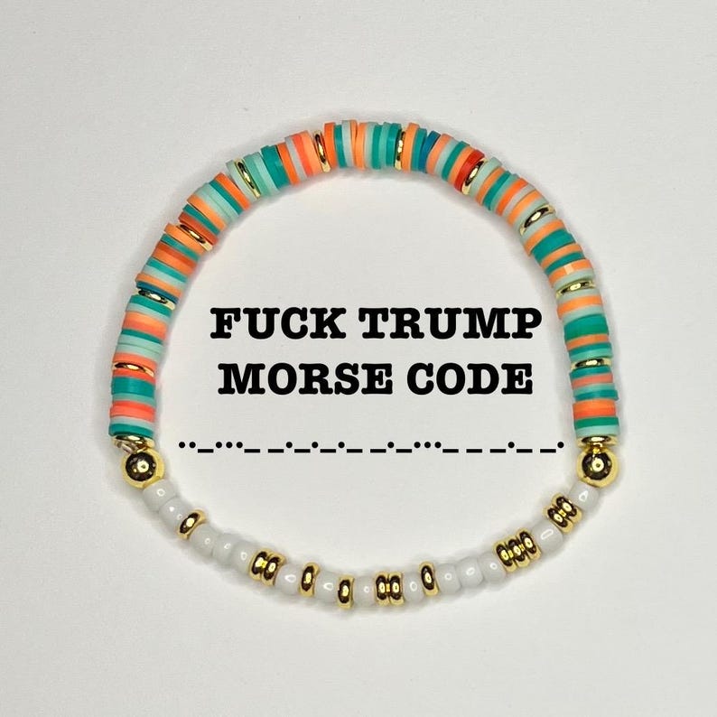 May include: A beaded bracelet with the text "FUCK TRUMP MORSE CODE" in black. The bracelet features colorful orange, teal, and gold beads, with white and gold beads at the bottom. The Morse code is written below the text.