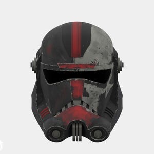 Op de afbeelding: Een zwart en rode helm met een verweerde uitstraling. De helm heeft een verticale rode streep en rode accenten rond het vizier en de onderkant van het gezicht. Het ontwerp bevat twee cirkelvormige elementen aan de zijkanten.
