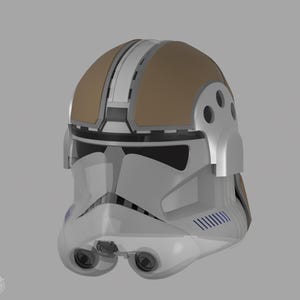 May include: A white and tan helmet with a visor and two eye pieces. The helmet has a tan top with a white stripe down the center. The helmet has a futuristic design with a series of vents and a chin piece.