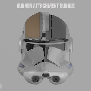 May include: A white and gray helmet with a brown visor and the text "GUNNER ATTACHMENT BUNDLE". The helmet has blue stripes and two eye pieces. The design is futuristic and appears to be a 3D render.