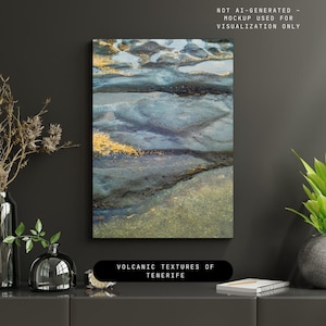 Könnte beinhalten: Abstrakte Leinwandkunst mit einem strukturierten Design in Blau-, Schwarz- und Goldtönen. Das Kunstwerk weist einen geschichteten Effekt auf, mit dem Text "VOLCANIC TEXTURES OF TENERIFE" unten. Das Stück wird an einer dunkelgrauen Wand ausgestellt.