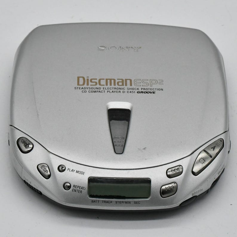 May include: Silver Sony Discman ESP2 CD player. Features include SteadySound Electronic Shock Protection, a digital display, and control buttons. The text "Discman ESP2" is printed on the device.