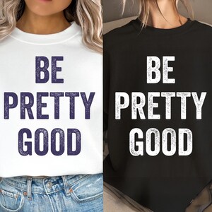 Pode incluir: Duas camisolas, uma branca e outra preta, cada uma exibindo o texto "BE PRETTY GOOD" em uma fonte arrojada e estilizada. A camisola branca tem texto azul marinho, enquanto a preta tem texto branco. Ambas são de gola redonda.