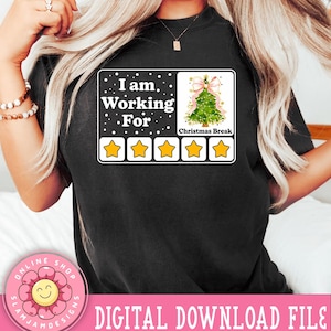 Peut inclure: T-shirt noir avec un graphique blanc qui dit "Je travaille pour les vacances de Noël" avec cinq étoiles jaunes sous le texte. Le graphique est dans le style d'un avis produit.
