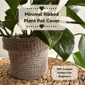 Peut inclure: Un cache-pot en crochet côtelé beige avec un bord supérieur replié, contenant une plante verte à feuilles. L'image comporte le texte Minimal Ribbed Plant Pot Cover et PDF Crochet Pattern For Beginners avec des icônes de cœur.