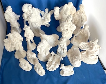 Może przedstawiać: Biały ceramiczny zestaw szopki bożonarodzeniowej z 18 elementami, w tym figurkami Maryi, Józefa, Dzieciątka Jezus, pasterzy, aniołów, zwierząt i wielbłąda.
