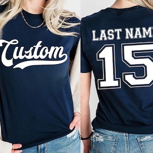 Puede incluir: Camiseta azul marino con la palabra "Custom" en escritura blanca en la parte delantera. La parte trasera de la camiseta muestra "LAST NAME" encima del n&uacute;mero "15" en letras blancas. La camiseta es de cuello redondo.