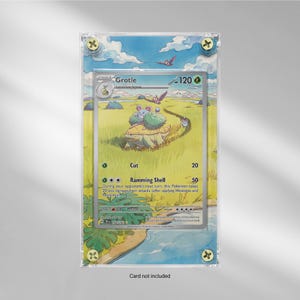 May include: A framed Grotle Pokémon card. The card features an illustration of a turtle-like creature in a grassy field with a blue sky. The card is in a clear acrylic frame with gold-colored screws.