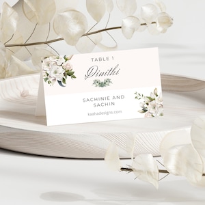 May include: White table number card with floral design. The card reads "Table 1 Dimithi Sachinie and Sachin kaahadesigns.com".