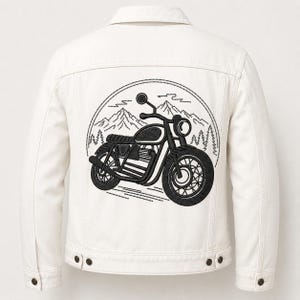May include: Off-white denim jacket featuring a black embroidered motorcycle design on the back. The motorcycle is set against a backdrop of mountains and trees within a circular frame. The jacket has a button-down front and two chest pockets.