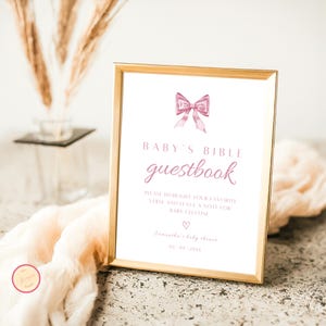 Puede incluir: Un cartel con marco dorado con un lazo rosa y el texto "BABY'S BIBLE guestbook" con instrucciones para resaltar un versículo favorito y dejar una nota para el bebé. El cartel también incluye el texto "Samantha's baby shower 09 09 20XX".