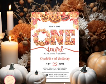 May include: A white invitation card with an orange and brown watercolour design featuring pumpkins and leaves. The text on the card reads "Isn't she one derful" and "Charlotte's 1st Birthday". The date of the party is "Sat 22 Oct" and the time is "At four o'clock in the afternoon". The location is "The Jumping Castle, Melbourne". The RSVP information is "By the 16th October 20XX to Lily Affe at 000 234 5568."