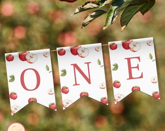 Può includere: Un banner con la parola "ONE" in lettere rosse, decorato con mele e foglie ad acquerello. Il banner è appeso a un sottile filo d'oro, perfetto per una festa di primo compleanno o a tema autunnale.