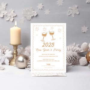 Puede incluir: Una tarjeta de invitaci&oacute;n blanca con letras doradas para una fiesta de Nochevieja. La tarjeta presenta una simple ilustraci&oacute;n de dos copas de champ&aacute;n con un borde dorado y copos de nieve. El texto dice "2025 Fiesta de A&ntilde;o Nuevo" e incluye los detalles de la fiesta: "Organizada por los Jamesons, s&aacute;bado 31 de diciembre a partir de las 12:00 p. m., Show Time Event Hall, 11 Holiday Drive Kingston, Nueva York 12401, RSVP a [email protected] antes del 15 de diciembre".
