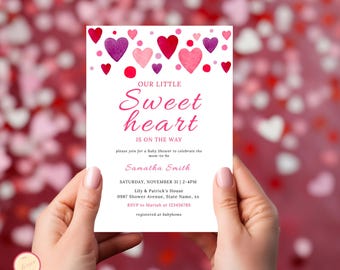 May include: A white baby shower invitation with pink and purple watercolor hearts. The text reads "Our Little Sweetheart is on the way". The invitation includes the date, time, location, and RSVP information.