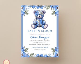 May include: Blue and white baby shower invitation with a teddy bear wearing a blue floral pattern. The invitation reads "Baby in Bloom" and includes the name "Olivia Thompson", the date and time of the shower, the location, and RSVP information.
