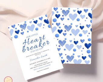May include: Blue and white baby shower invitation with a watercolor heart pattern. The text reads "Our Little Heartbreaker is on the way".