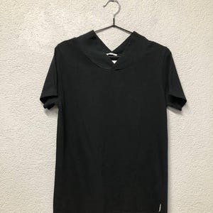 Könnte beinhalten: Schwarzes T-Shirt mit kurzen Ärmeln, V-Ausschnitt und Kapuze.