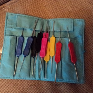 May include: A blue, teal, and black fabric case with a set of 10 colorful crochet hooks. The hooks are arranged in the case with their handles facing up.