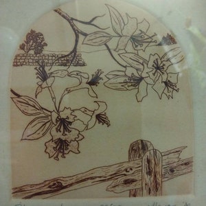 Op de afbeelding: Een zwart-witte print van een bloeiende bloem met een houten hek op de voorgrond. De print is getiteld "Blossoming Amour" en genummerd 95/250. De handtekening van de kunstenaar is "Aleman '80".