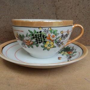 Vintage tea cup and saucer set white peach gold trim with checkered flags and yellow and orange flowers