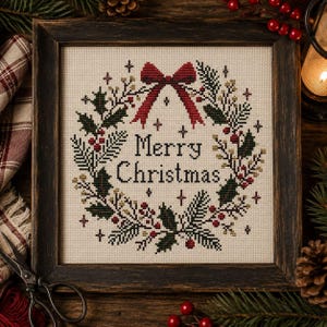 May include: A square cross-stitch embroidery in a dark wooden frame featuring a holiday wreath design. The wreath is composed of green pine needles, holly leaves, and red berries, topped with a red bow. The text Merry Christmas is centred.