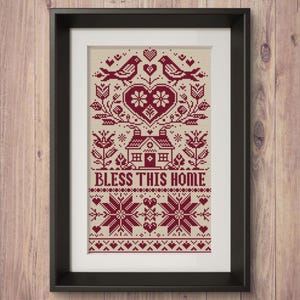 May include: Framed cross-stitch art with a cream background and burgundy design. The design includes birds, hearts, flowers, a house, and the text "BLESS THIS HOME." The artwork is in a black frame, suitable for home decor.