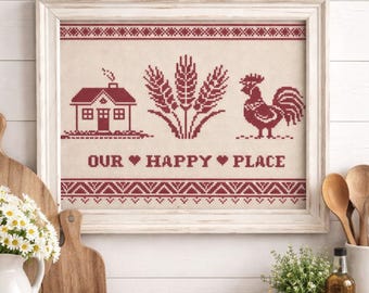 May include: Framed cross-stitch artwork featuring a red house, wheat stalks, and a rooster on a beige background. The text "OUR HAPPY PLACE" is stitched below the images. The frame is white.