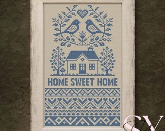Puede incluir: Un bordado de punto de cruz enmarcado con un diseño azul y blanco. La obra de arte representa dos pájaros sobre una casa con el texto "HOME SWEET HOME". El marco blanco tiene un acabado envejecido, añadiendo un toque rústico.