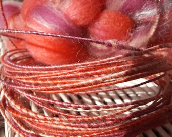 Wool fiber wire in bright coral, pink, and purple.