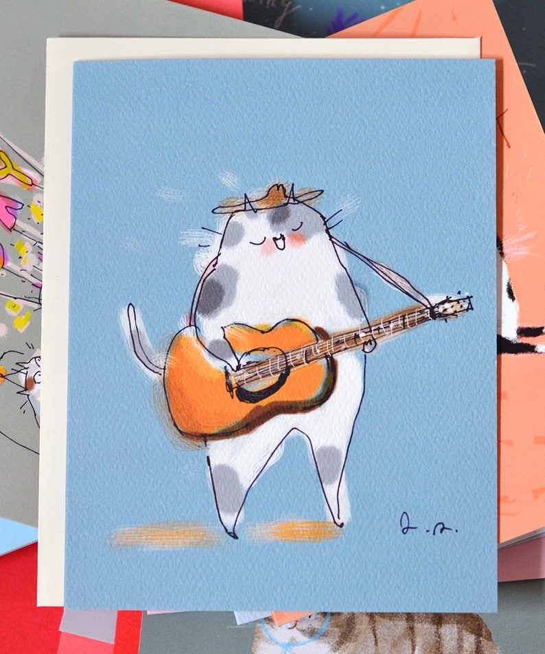 May include: A white cat with gray spots wearing a brown hat plays a brown acoustic guitar. The cat is singing and has its eyes closed. The background is light blue.