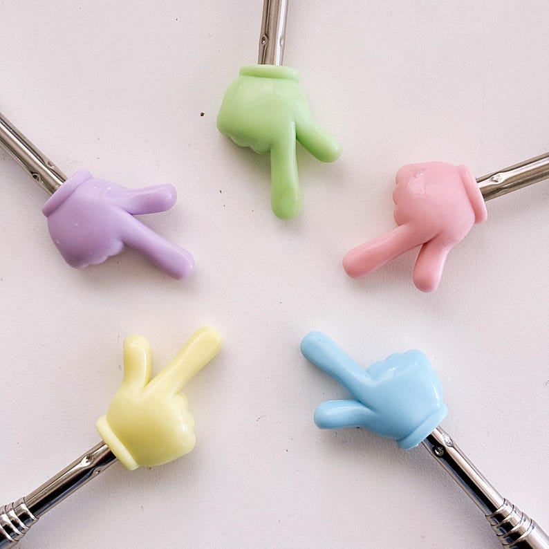 K&ouml;nnte beinhalten: F&uuml;nf bunte, handf&ouml;rmige Stifte-Topper aus Kunststoff in verschiedenen Farben: hellgr&uuml;n, lila, rosa, gelb und hellblau. Jeder Topper hat zwei Finger, die in verschiedene Richtungen zeigen.