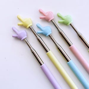 K&ouml;nnte beinhalten: F&uuml;nf ausziehbare Selfie-Sticks mit verschiedenen farbigen Handgriffen. Die Griffe sind pastellrosa, gelb, blau, gr&uuml;n und lila.