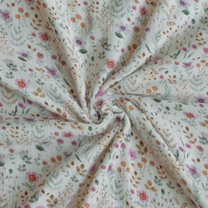 Può includere: Tessuto bianco sporco con un delicato motivo floreale. Il design presenta piccoli fiori rosa, viola e arancioni, insieme a foglie verdi e marroni. Il tessuto è morbido e fluido, con pieghe e pieghe visibili.