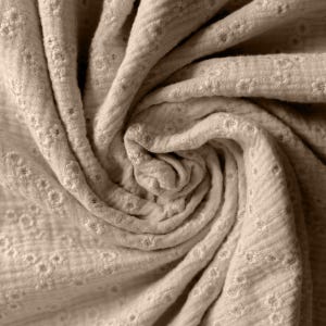 Op de afbeelding: Een close-up van een beige stof met een subtiel reli&euml;fpatroon. De stof is zacht en textuurrijk, met een licht gerimpelde uitstraling.