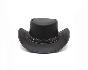 Puede incluir: Un sombrero de vaquero de cuero negro con un ala ancha y curva y una copa estructurada. El sombrero está adornado con una banda de cuero trenzado decorativa, costuras blancas en contraste y pequeños remaches metálicos en la base de la copa.