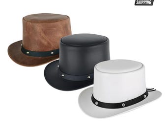 Puede incluir: Tres sombreros de copa en marrón, negro y blanco. Cada sombrero presenta una copa plana, un ala curva y una banda oscura alrededor de la base decorada con pequeños remaches metálicos plateados espaciados uniformemente. El sombrero marrón es texturizado.