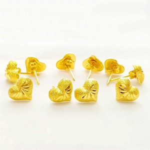 May include: A set of six gold heart-shaped earrings. The earrings are small and have a textured surface.