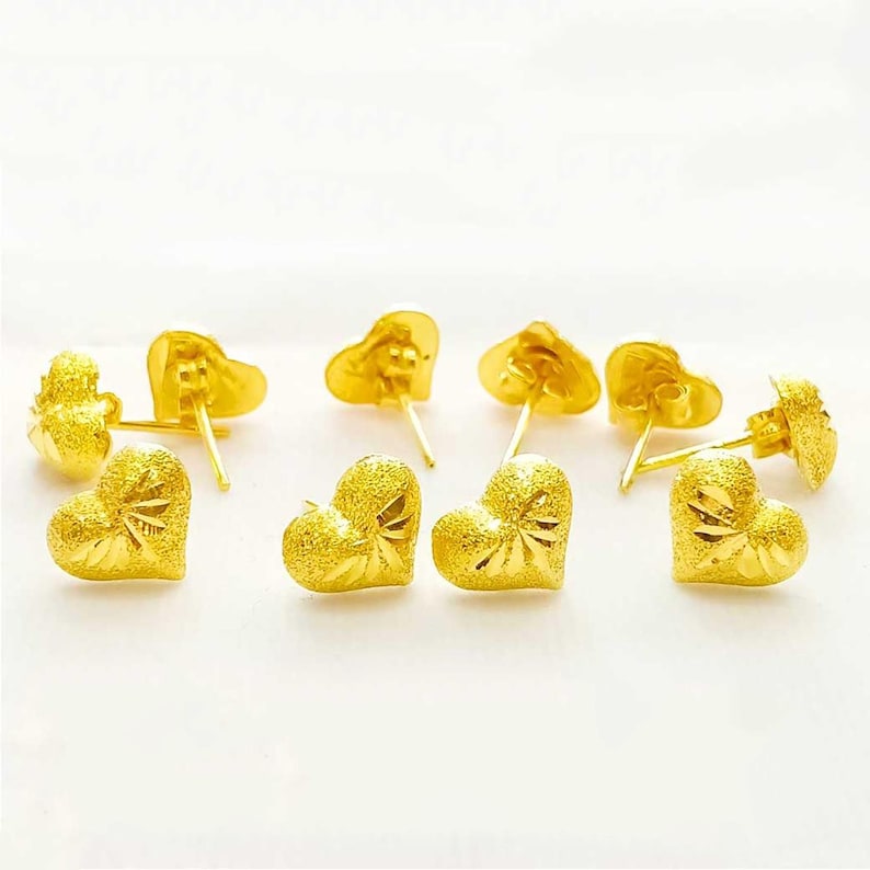 May include: A set of six gold heart-shaped earrings. The earrings are small and have a textured surface.