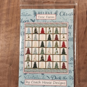May include: A Christmas-themed fabric panel kit in a clear plastic sleeve. The panel features a grid of Christmas trees in various colors. The text "Tree Farm" and "by Coach House Designs" are visible.