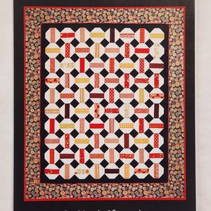 May include: A quilt pattern titled "Striped Snowballs" by Marcia Harmening, Happy Stash Quilts. The quilt design features a repeating pattern of red, yellow, and brown rectangles on a white background, with black squares. The border has a decorative pattern.