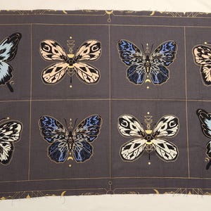 May include: A fabric panel featuring eight butterfly designs in a grid pattern. The butterflies have intricate wing patterns in shades of blue, black, and cream, with gold accents. The background is a dark gray with gold geometric lines. The text "SARAH WATTS" and "TIGER FLY" is visible.