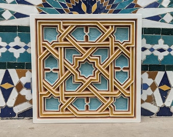Könnte beinhalten: Quadratische Wandkunst mit weißem Rahmen und geometrischem Muster. Das Design verwendet ineinandergreifende Formen in Gold, Beige und Hellblau. Der Hintergrund ist ein Mosaikfliesenmuster in Blau, Türkis und Weiß.