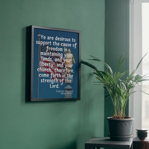 May include: A framed print with a black frame and a blue background. The print features a quote from Captain Moroni, a historical figure from the Book of Mormon, that reads: "Ye are desirous to support the cause of freedom in maintaining your lands, and your liberty, and your church; therefore, come forth in the strength of the Lord." The quote is attributed to Captain Moroni and the scripture reference is Alma 60:25.