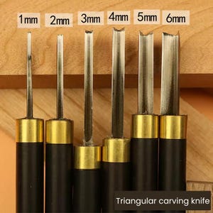 May include: Set of six triangular carving knives with black handles and gold-colored metal tips. The knives are arranged in order of size, from 1 mm to 6 mm. The text "Triangular carving knife" is visible at the bottom of the image.